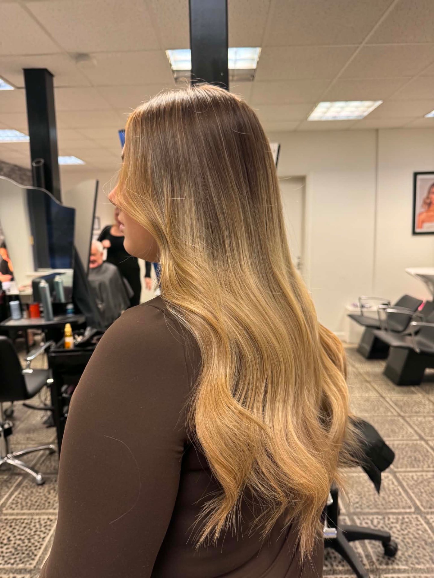 Long blonde balayage with soft waves seen from the side