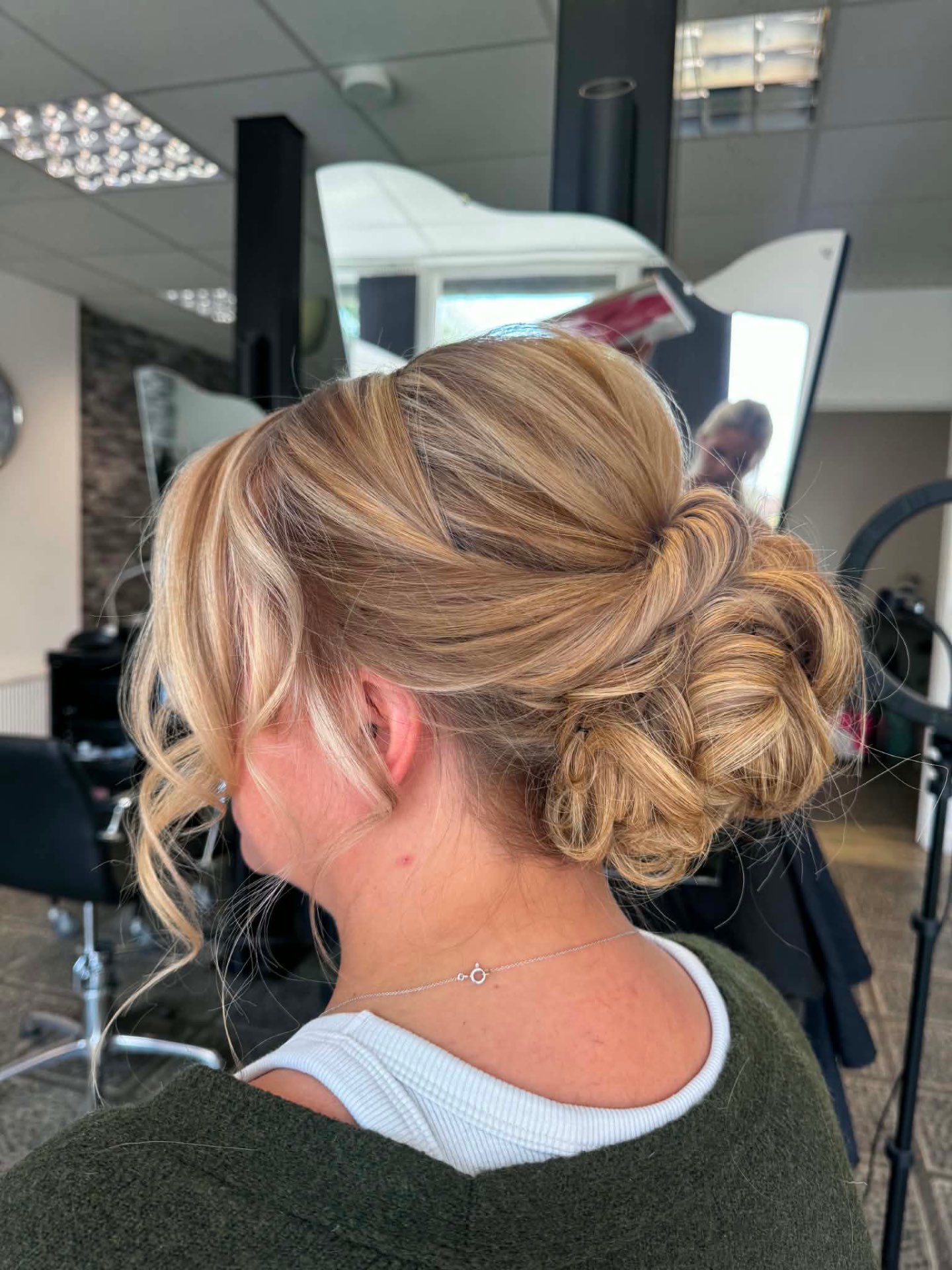 Soft blonde side bun with loose face-framing tendrils